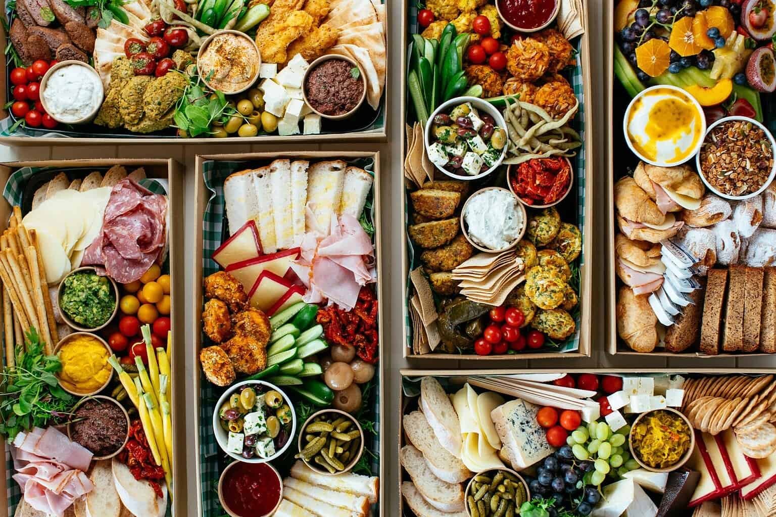 Assorted gourmet catering platters with cheeses, meats, fruits, and dips for events.