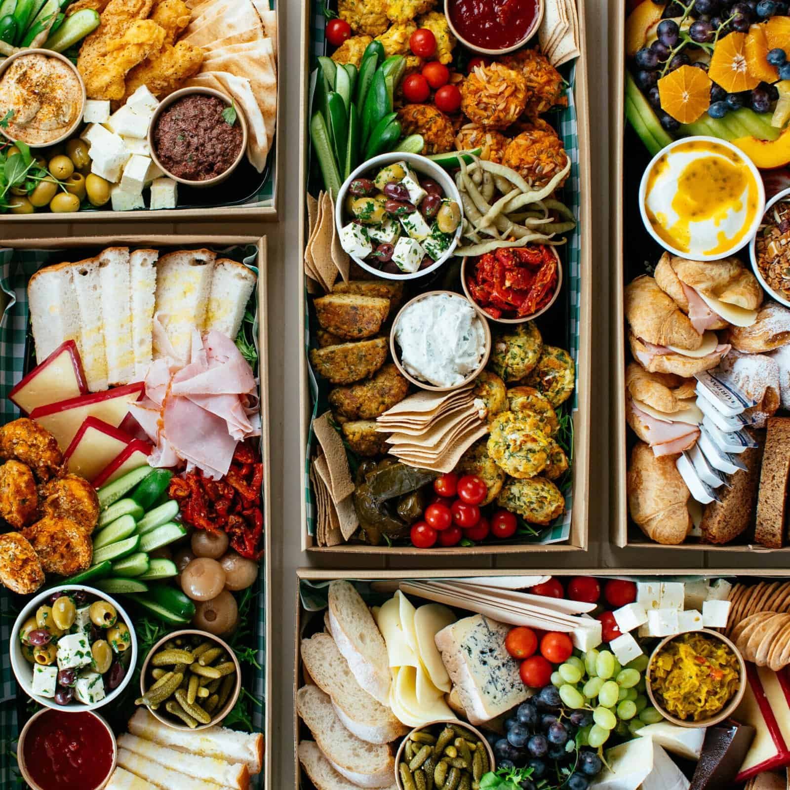 Assorted gourmet catering platters with cheeses, fruits, and finger foods.